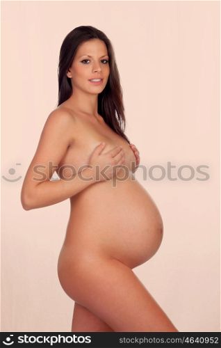 Delicate pose of a pregnant woman with naked torso on a orange background