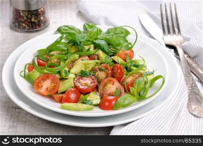 Delicate slices of avocado with tomatoes, dressed pesto sauce.