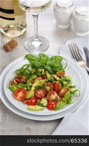 Delicate slices of avocado with tomatoes, dressed pesto sauce.