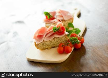 delicicious ham tomato sandwich with fresh parsley on wooden table with day light illumination
