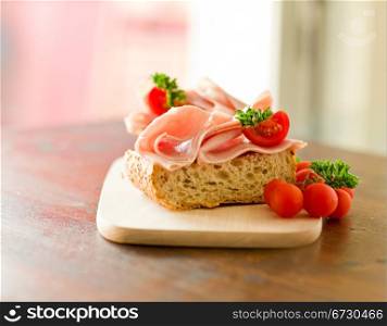 delicicious ham tomato sandwich with fresh parsley on wooden table with day light illumination