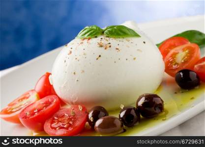 deliciious buffalo mozzarella with cutted cherry tomatoes and olives over extra vergin oil