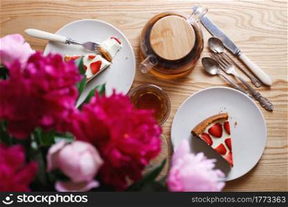 delicious and beautiful breakfast. cheesecake with strawberries on a wooden background with a bouquet of peonies