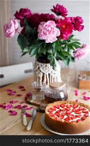 delicious and beautiful breakfast. cheesecake with strawberries on a wooden background with a bouquet of peonies