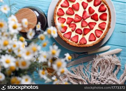 delicious and beautiful breakfast. cheesecake with strawberries on a wooden background with a bouquet of daisy
