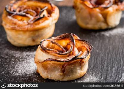 Delicious apple cakes with sugar on wooden table.