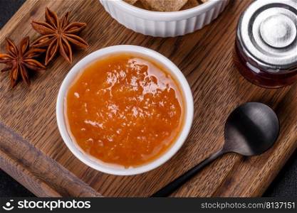 Delicious apricot jam, milk and sugar on a wooden cutting board against a dark concrete background. Delicious apricot jam, milk and sugar on a wooden cutting board