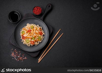 Delicious Asian cuisine dish with rice noodles, peppers, mushrooms and spices on a dark concrete background