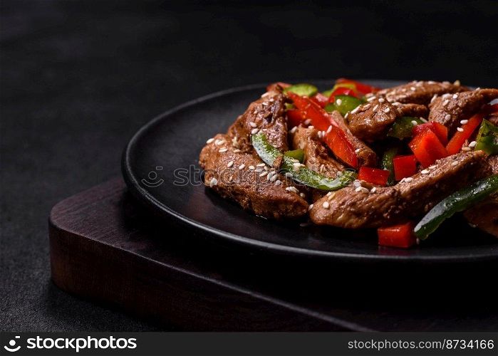 Delicious Asian teriyaki meat with red and green bell peppers and sesame seeds close-up on a plate on the table. Delicious Asian teriyaki meat with red and green bell peppers