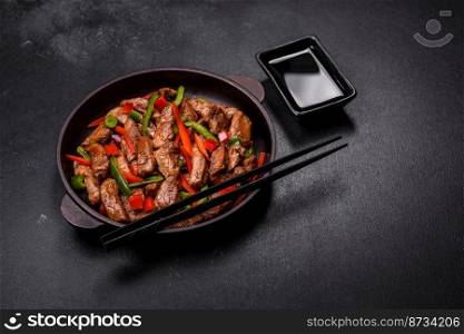 Delicious Asian teriyaki meat with red and green bell peppers and sesame seeds close-up on a plate on the table. Delicious Asian teriyaki meat with red and green bell peppers