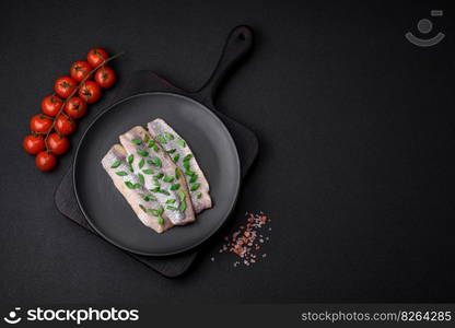 Delicious Atlantic herring marinated with salt and spices in oil on a dark concrete background