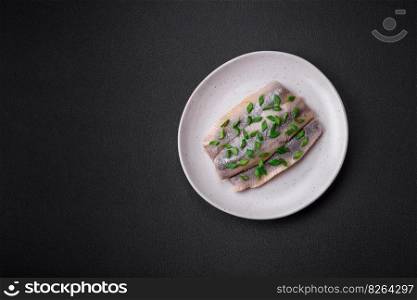 Delicious Atlantic herring marinated with salt and spices in oil on a dark concrete background