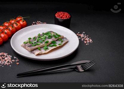 Delicious Atlantic herring marinated with salt and spices in oil on a dark concrete background