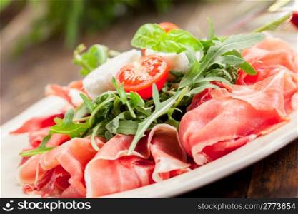 delicious bacon arugula salad with mozzarella on wooden table