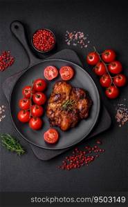 Delicious baked chicken meat with salt, spices and herbs on a dark concrete background