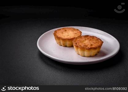 Delicious baked cupcake or tartlet with cheese and raisins on a dark textured background