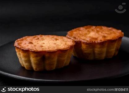 Delicious baked cupcake or tartlet with cheese and raisins on a dark textured background