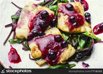 Delicious baked fish with berry sauce. Stewed pangasius with blueberries. Baked fish,pangasius on white plate