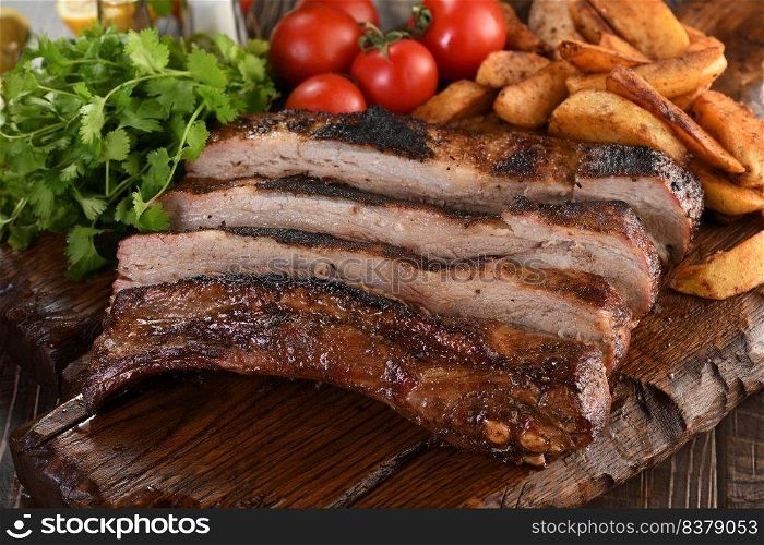 Delicious Baked Grilled Sliced pork belly with barbeque  sauce plating on wooden plate,  herbs and vegetables and potatoes