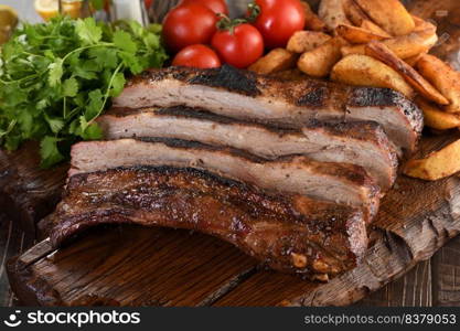 Delicious Baked Grilled Sliced pork belly with barbeque  sauce plating on wooden plate,  herbs and vegetables and potatoes