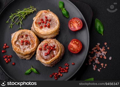 Delicious baked meat roll wrapped in bacon with salt, spices and herbs on a dark concrete background