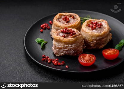 Delicious baked meat roll wrapped in bacon with salt, spices and herbs on a dark concrete background