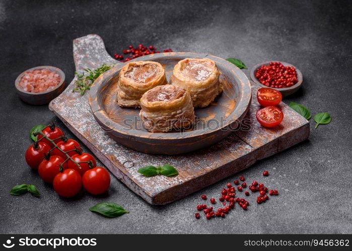 Delicious baked meat roll wrapped in bacon with salt, spices and herbs on a dark concrete background