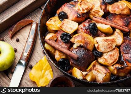 Delicious baked meat stew in apples on old wooden table. Stewed meat with apples.