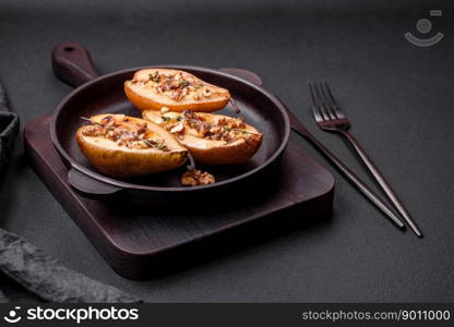 Delicious baked pear with dorblu cheese, walnut and honey on a textured concrete background. Vegetarian dish