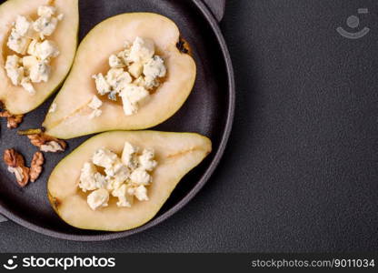 Delicious baked pear with dorblu cheese, walnut and honey on a textured concrete background. Vegetarian dish