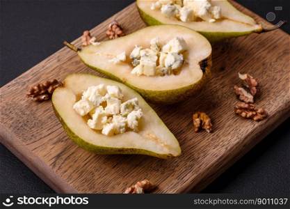 Delicious baked pear with dorblu cheese, walnut and honey on a textured concrete background. Vegetarian dish