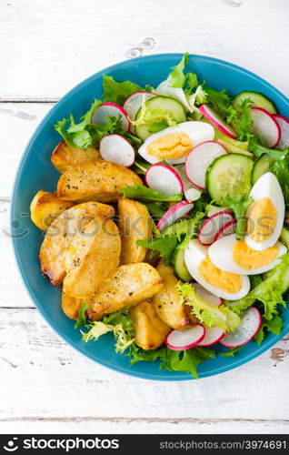 Delicious baked potato, boiled egg and fresh vegetable salad of lettuce, cucumber and radish. Summer menu for detox diet