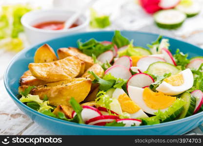 Delicious baked potato, boiled egg and fresh vegetable salad of lettuce, cucumber and radish. Summer menu for detox diet