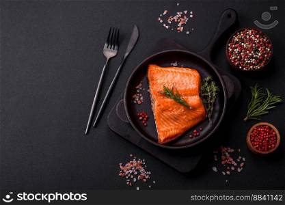 Delicious baked salmon red fish steak with spices and herbs on a dark concrete background