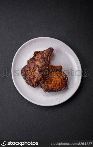 Delicious beef or pork steak on the bone grilled with spices and rosemary on a dark concrete background