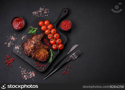 Delicious beef or pork steak on the bone grilled with spices and rosemary on a dark concrete background