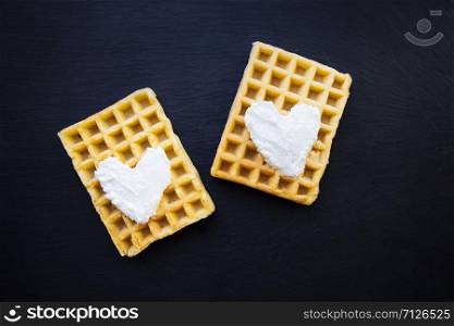 Delicious belgian waffles with cream on a black background. Delicious belgian waffles with cream on a black background.