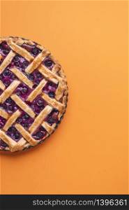 Delicious blueberries cake with a lattice crust. Fruits filling pie above view on orange background. Homemade blueberry tart.