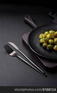 Delicious boiled Brussels sprouts on a ceramic plate on a dark concrete background. Vegetarian food
