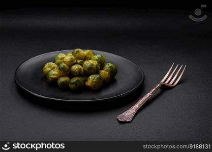 Delicious boiled Brussels sprouts on a ceramic plate on a dark concrete background. Vegetarian food