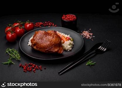 Delicious boiled rice with chicken and vegetables or risotto with salt, spices and herbs on a ceramic plate on a dark concrete background