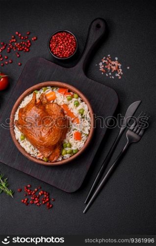 Delicious boiled rice with chicken and vegetables or risotto with salt, spices and herbs on a ceramic plate on a dark concrete background