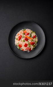 Delicious boiled rice with peppers, peas, asparagus beans and carrots on a textured concrete background