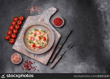 Delicious boiled rice with peppers, peas, asparagus beans and carrots on a textured concrete background