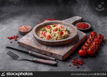 Delicious boiled rice with peppers, peas, asparagus beans and carrots on a textured concrete background