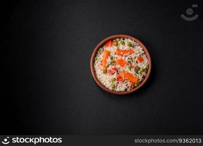 Delicious boiled rice with vegetables or risotto with salt, spices and herbs on a ceramic plate on a dark concrete background