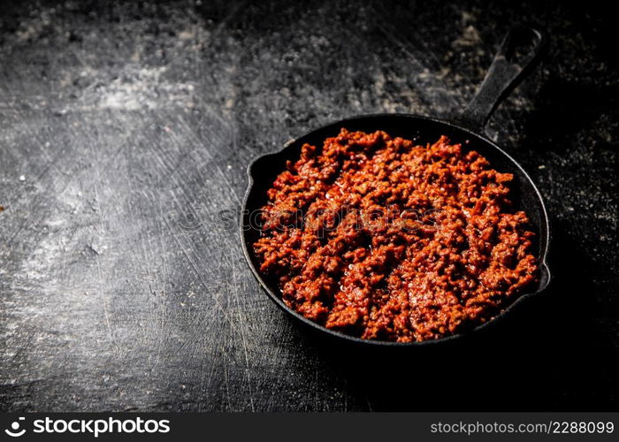 Delicious bolognese sauce in a frying pan. On a black background. High quality photo. Delicious bolognese sauce in a frying pan.