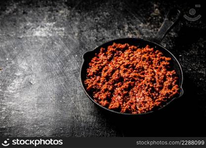 Delicious bolognese sauce in a frying pan. On a black background. High quality photo. Delicious bolognese sauce in a frying pan.