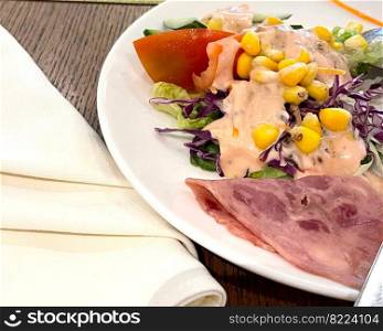 delicious breakfast, ham and fresh summer salad on white plate, on wooden table, view from above, good for your multimedia content background