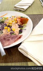 delicious breakfast, ham and fresh summer salad on white plate, on wooden table, view from above, good for your multimedia content background